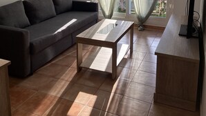 Una sala de estar moderna con un sofá gris oscuro, una mesa de centro de madera y un mueble para televisor.