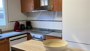 Una cocina con armarios de madera, una campana extractora de acero inoxidable, un refrigerador blanco y una encimera con un tazón grande.
