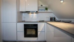 Eine moderne Küche mit weißen Schränken, einem eingebauten Backofen und einer Arbeitsplatte mit Toaster und zwei Drahtkörben.