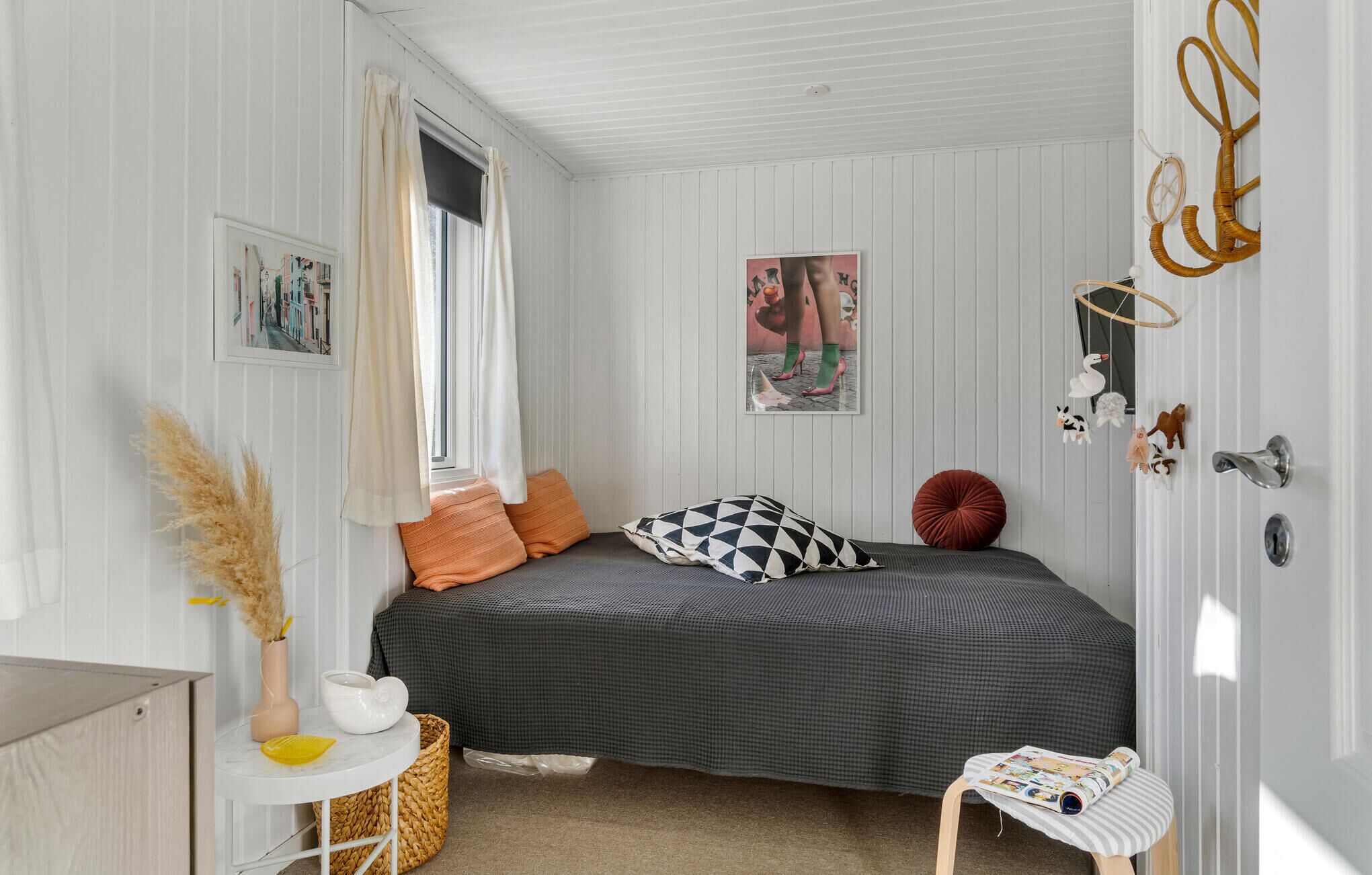 Een slaapkamer met een bed, een klein tafeltje, een mand en een deur met decoratie.