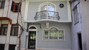 A two-story building with a balcony, a black gate, and a window with a decorative iron grille. - Cozy Home Next to Green Mosque (Bursa)