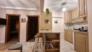 A modern kitchen with marble countertops, wooden cabinets, and a central island with stools. - Cozy Home Next to Green Mosque (Bursa)