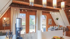 Un intérieur chaleureux et accueillant, avec des éléments en bois, un coin repas, une machine à café et un panier de fruits.