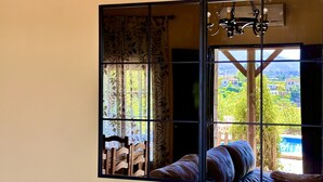 A room with a large window, a bed, and a hanging light fixture. - Finca La Panorámica (Málaga)