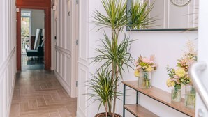 A hallway with a potted plant, a wooden shelf with vases, and a sign for Four Acanfora Suites. - Four - Acanfora Suites (Pompei)