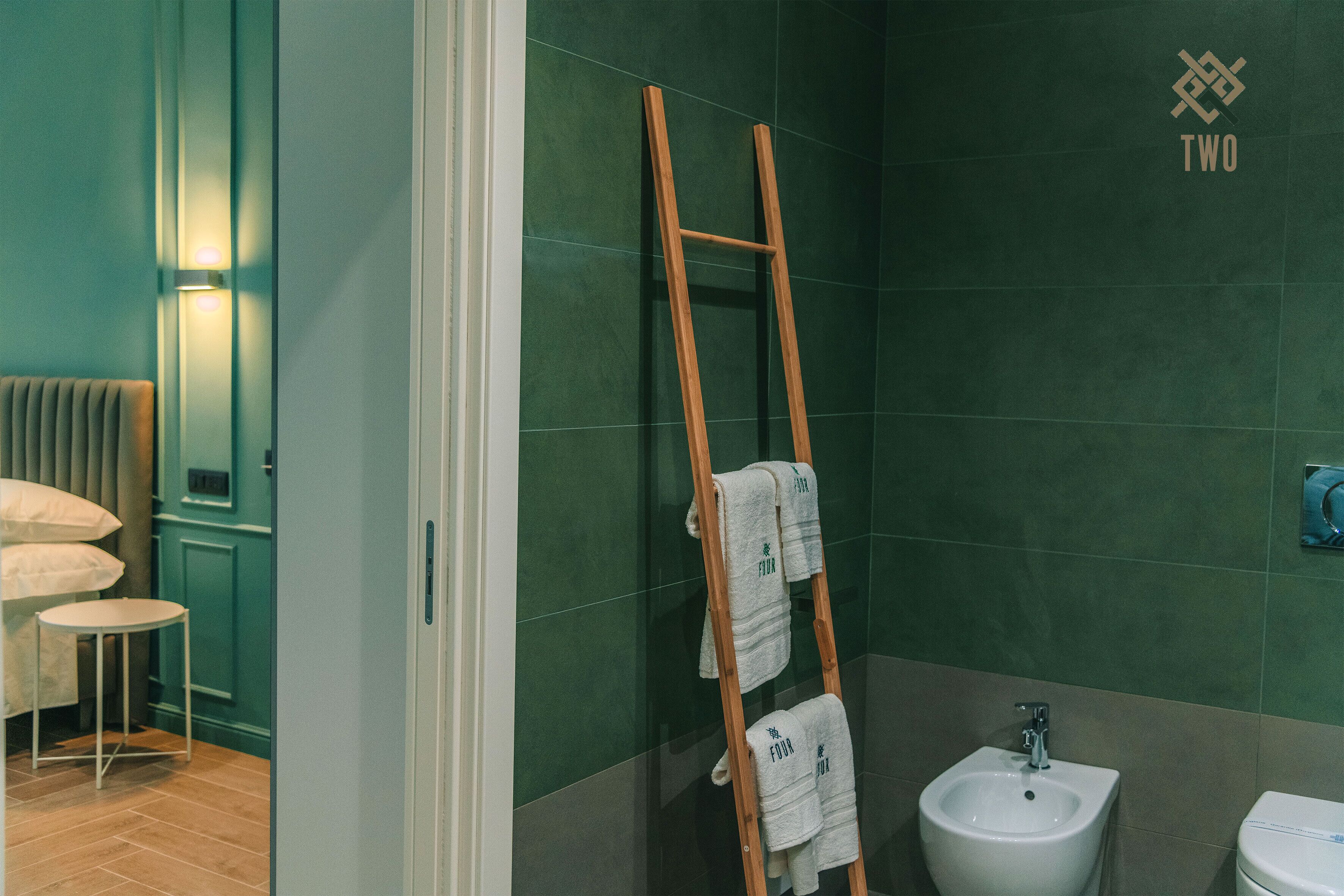 Un baño con una escalera de madera, un bidé y un perchero con toallas.