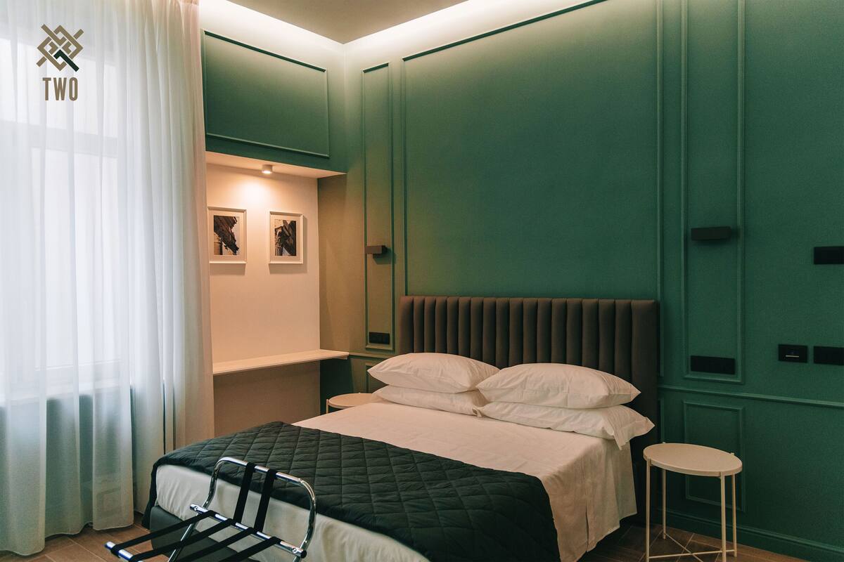 A neatly arranged bedroom with a bed, bedside table, and a small stool.