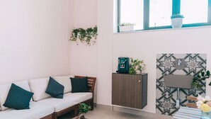 A modern living room with a sofa, coffee table, and a cabinet with plants. - Four - Acanfora Suites (Pompei)