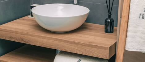 A bathroom with a white ceramic sink, wooden vanity, and a towel with "FOUR" on it.