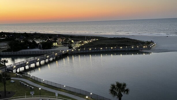 A resort with a swimming pool, a waterfront promenade, and a view of the ocean at sunset. - New for June 2023 All New!! Taking Reservations Now w/Great Rates! (Myrtle Beach)
