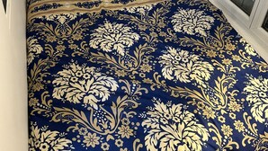 A bed with a dark blue and gold floral bedspread and matching pillows. - Chic and modern apartment (Châtillon)