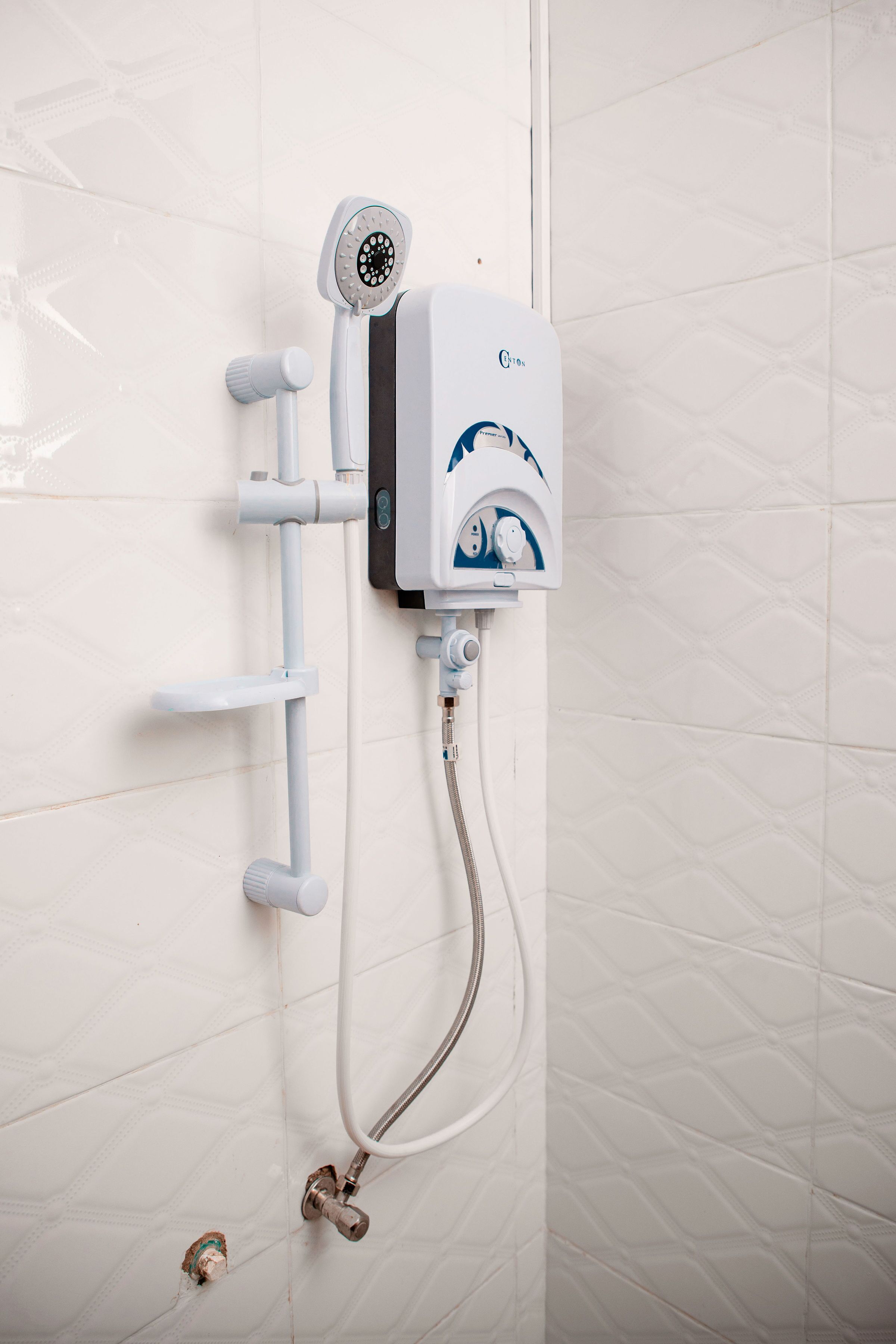 A wall-mounted shower unit with a handheld showerhead and a control panel.