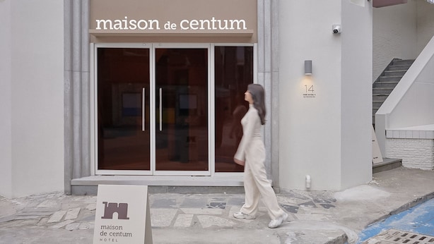 A hotel entrance with a sign reading "maison de centum".