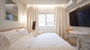 A hotel room with a bed, a TV, a small table, and a chair.