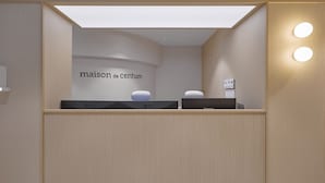 A reception area with a sign reading "maison de centum" and two LG monitors on a counter.