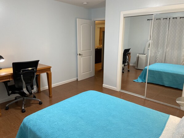 A bedroom with a bed, a desk, and a chair.