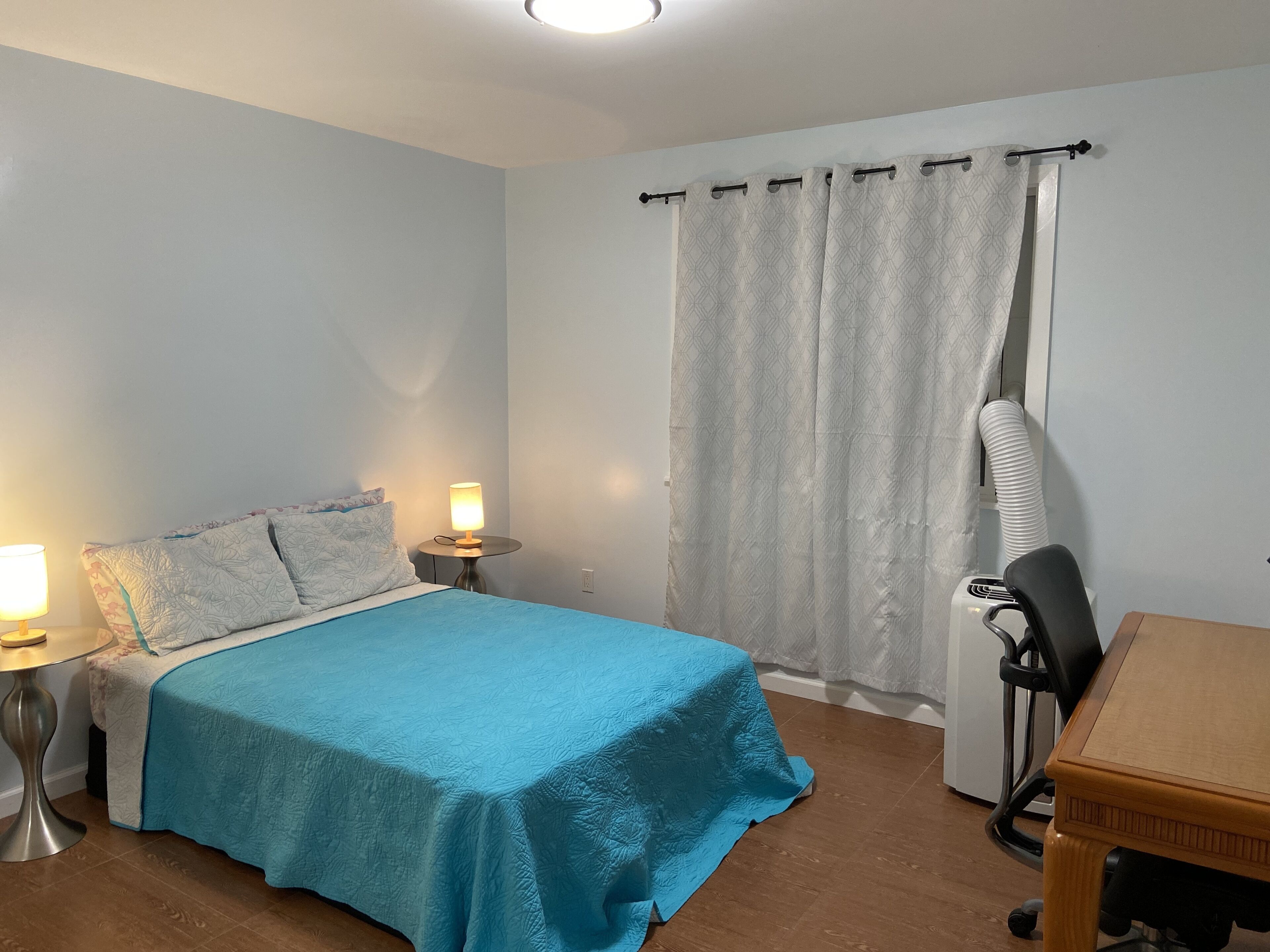 Ein Schlafzimmer mit einem Bett, Nachttischlampen, einem Schreibtisch und einem Stuhl.