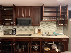 A kitchen with dark wooden cabinets, a microwave, a toaster, and a sink.