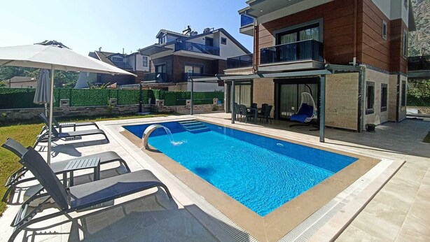 A modern two-story house with a swimming pool, outdoor seating, and a covered patio area. - Villa Kayahan Göcek (Fethiye)