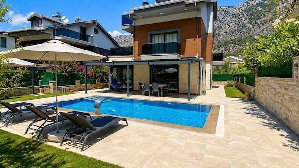 A modern two-story house with a swimming pool, outdoor seating, and a mountain backdrop. - Villa Kayahan Göcek (Fethiye)