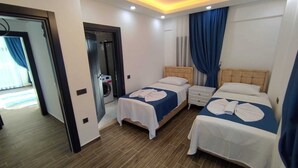 A hotel room with two beds, a washing machine, and a ceiling light fixture. - Villa Kayahan Göcek (Fethiye)