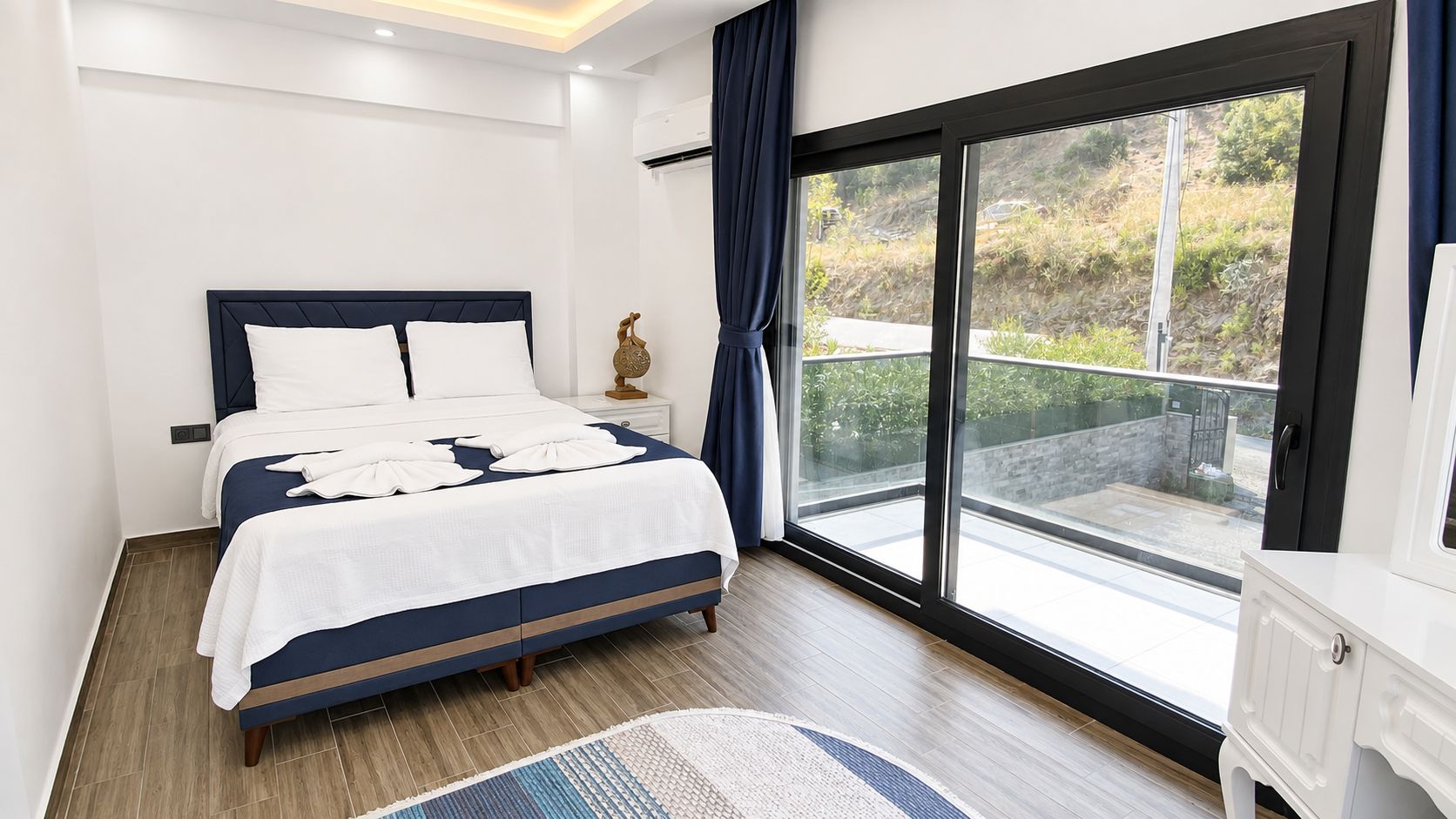 Un dormitorio con cama, mesita de noche, ventana y radiador.