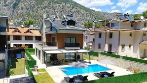 A modern villa with a swimming pool, outdoor seating, and solar panels. - Villa Kayahan Göcek (Fethiye)