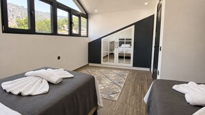 Ein Schlafzimmer mit zwei Betten, einem großen Fenster und Blick auf einen Berg.