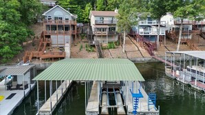 Une propriété située au bord de l’eau, comprenant plusieurs maisons reliées par des passerelles, un quai avec des bateaux et une zone abritée pour lancer les bateaux à l’eau.