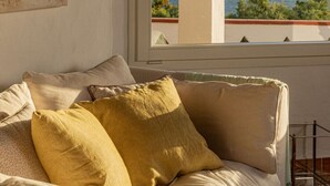 Un sofá color beige con varios cojines en una habitación con ventana que da a un balcón.