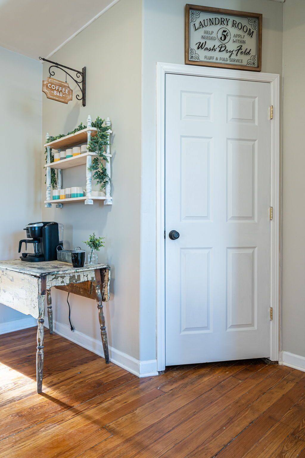 A room with a white door, a coffee bar, and a laundry room sign.