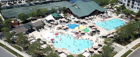 Un complexe hôtelier doté de plusieurs piscines, de chaises longues et d’un grand bâtiment surmonté d’un toit végétalisé.