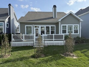 Stunning two-story home with a central entrance, porch, and well-manicured lawn.