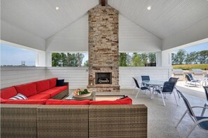 Relax in a spacious outdoor living area with a fireplace, comfortable seating, and a round dining table.