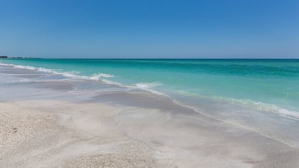 Una spiaggia con acque turchesi cristalline e una riva sabbiosa.