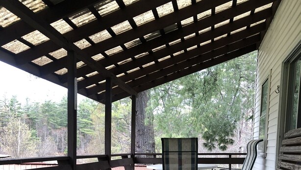 A wooden deck with benches and a table, surrounded by trees.