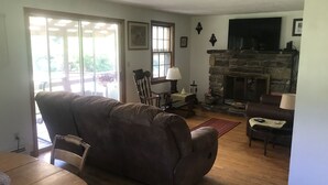 A cozy living room with a stone fireplace, a large window, and a comfortable sofa.