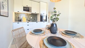 A modern kitchen with white cabinets, a microwave, and a dining area with a round table set for four.