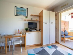 Un espacio habitable compacto con comedor, televisor y kitchenette.