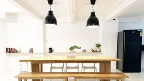 Cuina moderna amb taula i banc de fusta, llums penjants i un frigorífic.
