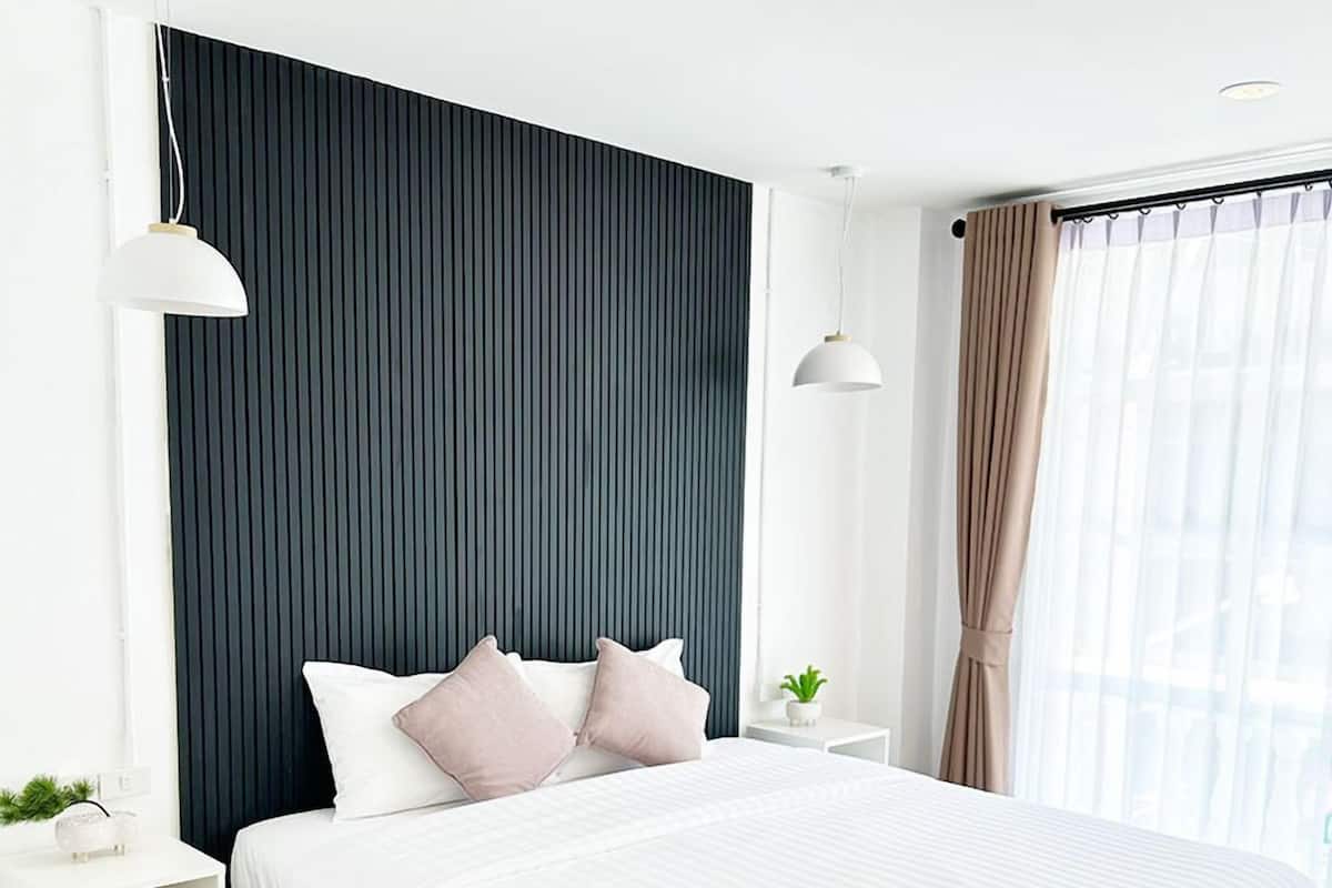 Un dormitorio moderno con una cama grande, una mesita de noche y una ventana con cortinas.