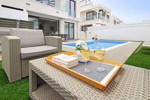 Relax in a comfortable outdoor space with a sofa and table, perfect for a leisurely moment by the pool.