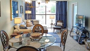 A dining area with a glass table, chairs, and a ceiling fan. - Walk-to-Beach Condo with Resort Pool (Biloxi)