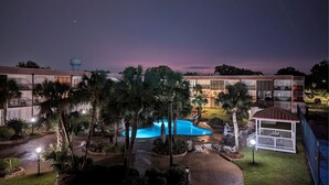 A modern hotel with a swimming pool, palm trees, and a well-lit outdoor area. - Walk-to-Beach Condo with Resort Pool (Biloxi)