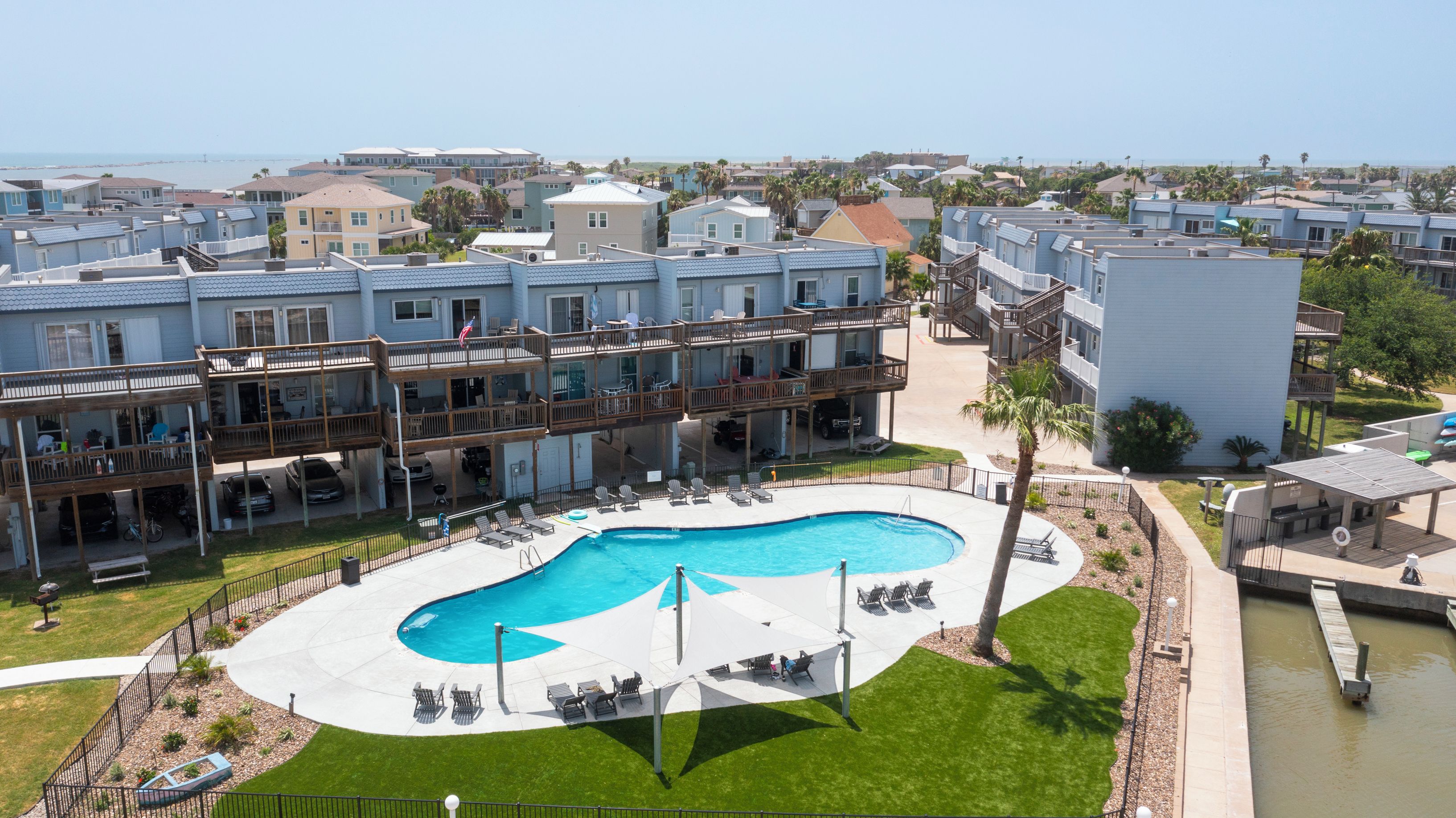 A multi-story hotel with a pool area, outdoor seating, and a view of the ocean.