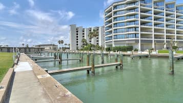 A waterfront hotel with multiple balconies, a marina, and a grassy area.