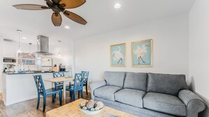 A modern living room with a grey sofa, a dining table with chairs, and a ceiling fan. - With the best amenities in Port Aransas! Large swimming pool, private lighted fi (Port Aransas)