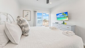 A bedroom with a bed, pillows, a ceiling fan, a television, and a window with a view of the outdoors. - With the best amenities in Port Aransas! Large swimming pool, private lighted fi (Port Aransas)
