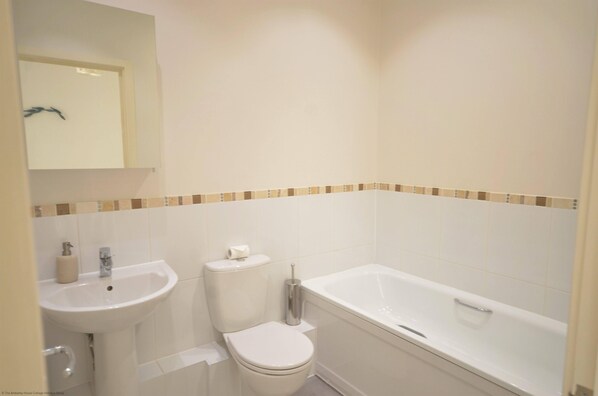 A bathroom with a sink, toilet, and bathtub. - Light, modern townhouse with patio, a minute from beach; child- and pet-friendly (Goring-by-Sea)