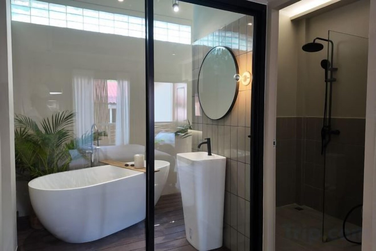A modern bathroom with a freestanding bathtub, a separate sink, and a glass-enclosed shower.